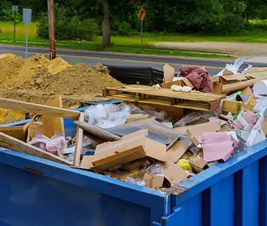 Blue construction debris container filled with rock and concrete rubble. Industrial garbage bin