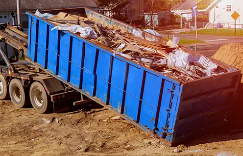 Industrial garbage bin blue construction debris container filled with rock and concrete rubble.